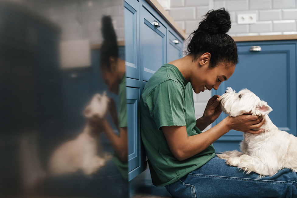 a woman smiling at a dog in her lap